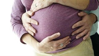 怀孕的妈妈用爸爸手在腹部