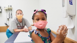 年轻女孩戴着面具在医生的办公室有护士